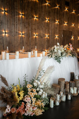 Romantic boho main table. Wedding decor with dried flowers floristry, stumps, and candles, boho style. Pampas grass