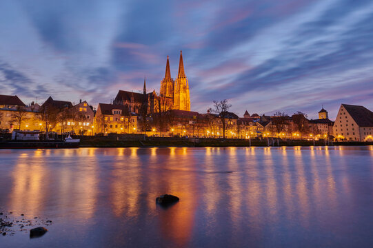 Outlook over the Danube River with the Gothic St Peter's Cathedral from the Marc​-Aurel-shore in the Old Town of Regensburg at dusk; Regensburg, Bavaria, Germany