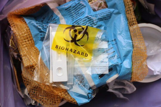 Used SARS Covid antigen test kit in the biohazard disposable bag thrown into a garbage can. 
