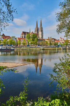 Outlook over the Danube River with the Gothic St Peter's Cathedral from the Marc​-Aurel-shore in the Old Town of Regensburg with a blue sky at sunset; Regensburg, Bavaria, Germany