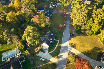 View from above of expensive residential houses between yellow fall trees in suburban area in South...