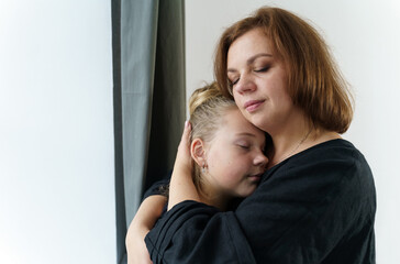 Mom hugs her teenage daughter, presses her to her chest.