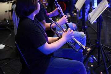 A person playing the trumpet by notes sitting in a jazz orchestra a close-up of a teenage musician with a musical instrument in his hand.Image concept leisure and creative hobby of teenagers - obrazy, fototapety, plakaty