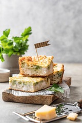 Chicken broccoli cheesy sliced casserole on wooden board on gray background with text space. Healthy food