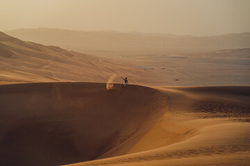 Fototapeta na wymiar Person sitting on the Moreeb Dunes at Rub Al Khali in the UAE