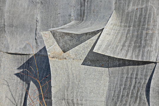 Detail of sheet metal patterns curling on the side of a corrugated metal shed patched together in winter; Nulato, Interior Alaska, Alaska, United States of America