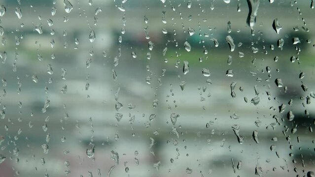 Raindrops on the window. Its raining outside. Close-up shot. View from the window to the road with passing cars.