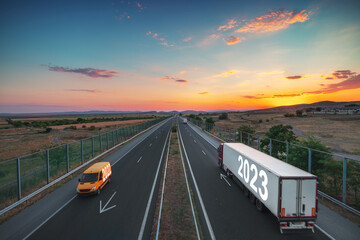 Driving on open road at beautiful sunset toward upcoming new year 2023. Logistic and transportation industry on highway.