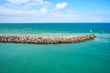 Close-up of a rock breakwater and boat moored at the end in the green water of the North Sea along the coast of Denmark; Hirtshals, Jutland, Denmark