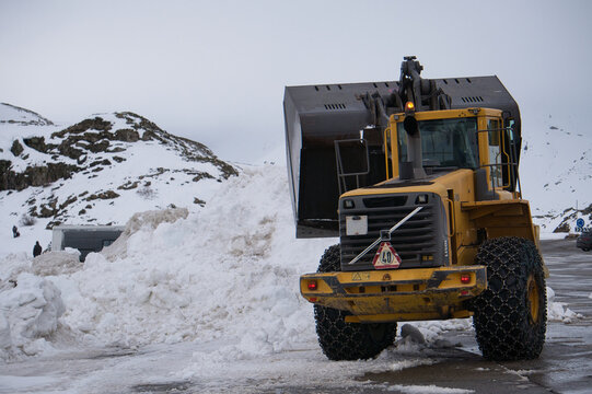 Quitanieves con cadenas amontonando nieve de la carretera. M&aacute;quina excavadora quitando nieve