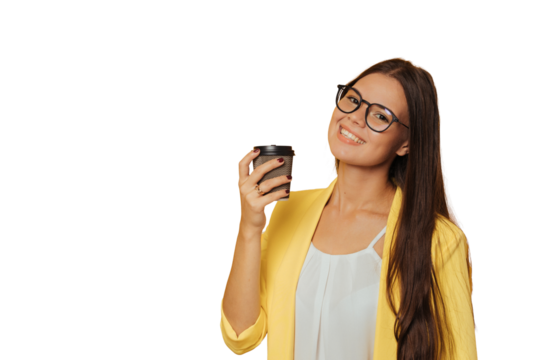 Cute girl dressed in yellow jacket and glasses holding cup of coffee, smiling broadly over transparent background with a copy space. Advertisement concept. Mockup, pretty italian young woman relaxing.