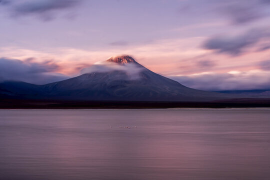 A slow shutter speed photograph catches the movements of the clouds around a high altitude volcano.