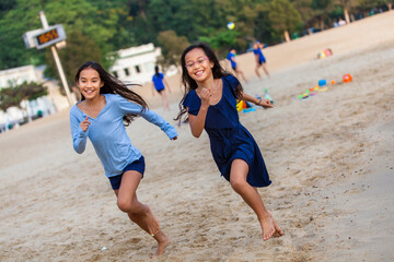 Two sisters racing on Repulse Bay Beach; Hong Kong, China