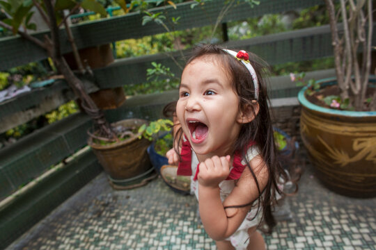 Young girl stands an an outdoor patio with a dramatic look while dancing great enthusiasm; Hong Kong, China