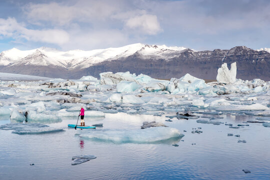 A Woman On An Inflatable Paddleboard Paddling On The Jokulsarlon Glacier Lagoon.