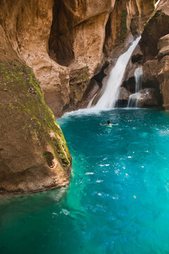A swimmer under the waterfall at Basin Bleu.