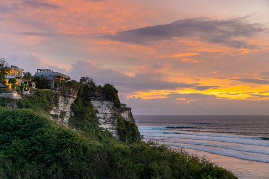 Oceanfront beach houses on the cliffs of the Bukit Peninsula at Uluwatu Beach, looking out to the Indian Ocean in South Bali at sunset; Uluwatu, Badung, Bali, Indonesia