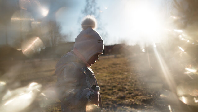 Portrait of a three-year-old girl in the backlight of the sun, sparkles in the foreground.