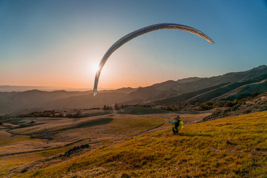 Paraglider pilot playing with his wing as the sun sets; San Ynez Valley, California, United States of America