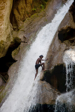 A man climbs the waterfall at Basin Bleu.