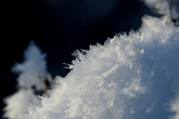 Białe płatki, kryształki, fraktale śniegu na ciemnym tle. Zbliżenie, makro. Różne formy kryształów lodu i płatków śniegu w zbliżeniu.