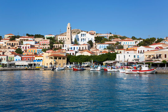 Traditional buildings and boats moored along the waterfront in the harbor at Emborio, the main town on Halki (Chalki) Island; Dodecanese Island Group, Greece