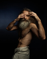 Homeless man with a thick beard on a dark background