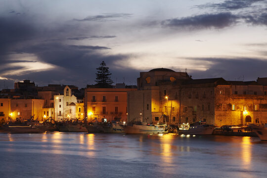 A dusk view of the fishing boats in the harbor of Trani.; Trani, Puglia, Italy.