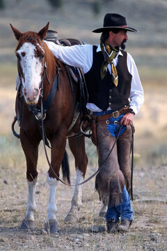 Cowboy waiting with horse; Seneca, Oregon, United States of America