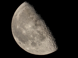 Half moon illuminated in a dark sky with details of the surface; South Shields, Tyne and Wear, England