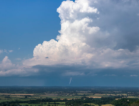 A bolt of lightning strikes beneath a huge thunderstorm updraft as it drifts over the English countryside; Brighton, East Sussex, England