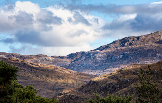 Harsh Scottish mountain range softened and enriched by shafts of autumn light; Strathcarron, Highland, Scotland