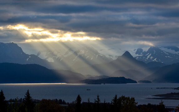Sun rays light up the Poot Peak and the Kenai Mountains across Kachemak Bay from Homer, Alaska, USA; Homer, Alaska, United States of America