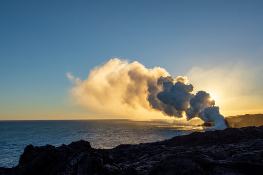 Lava ocean entry on the Big Island of Hawaii lights up the darkness and spews a huge column of noxious gas; Island of Hawaii, Hawaii, United States of America