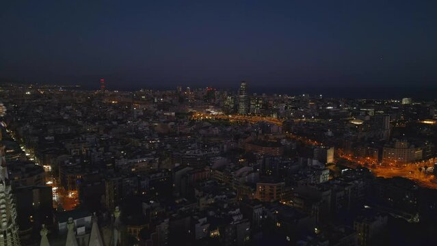 Evening view of downtown Barcelona flying backward revealing Sagrada Familia