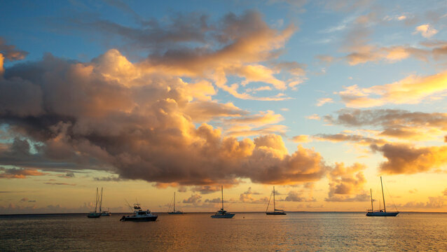 Sailboats anchored off shore at sunset; Tahaa, French Polynesia