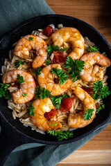 Shrimp scampi with pasta (orzo) garnished with parsley and grape tomatoes