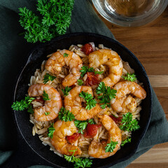 Shrimp scampi with pasta (orzo) garnished with parsley and grape tomatoes