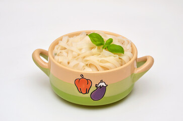 rice noodles in a bowl garnished with basil on light background close-up