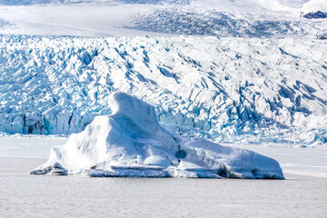 un iceberg emerge dalla laguna ghiacciata al centro dell'immagine, sullo sfondo la lingua del...