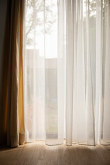 Transparent white curtain tulle on a sunny day, rays of sunlight penetrate the room, view from...