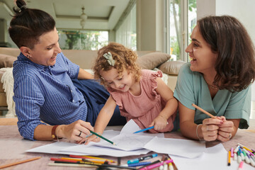 Happy mothers and their little daughter drawing pictures together