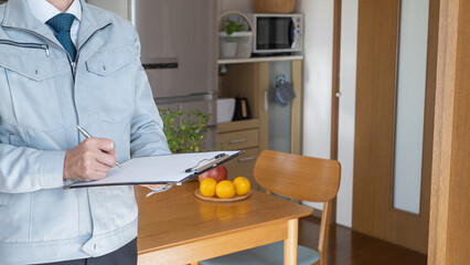 リビング・キッチンを点検する作業服の男性｜リフォーム調査・見積り　イメージ