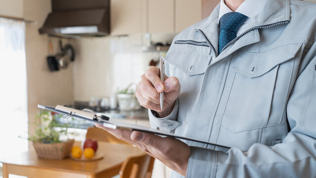 リビング・キッチンを点検する作業服の男性｜リフォーム調査・見積り　イメージ