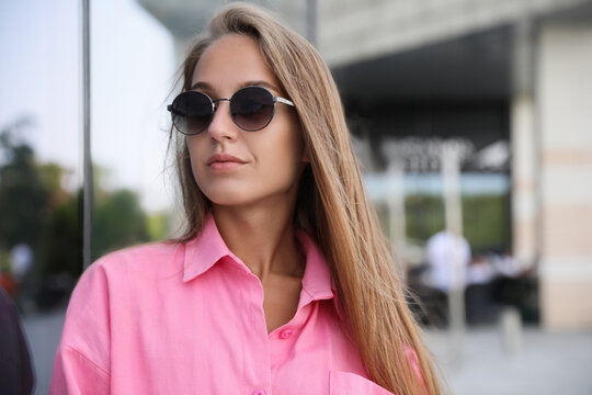 Beautiful young woman in stylish sunglasses on city street