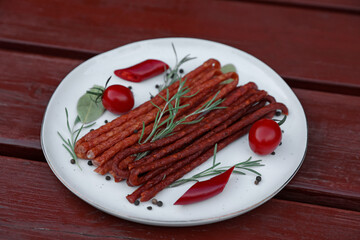 Tasty dry cured sausages (kabanosy) and ingredients on wooden table