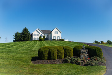 Large modern white stone house on a hill with a huge green lawn. Country two-story house. Blue sky...