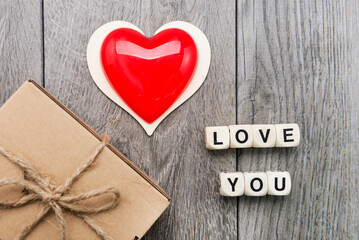 heart . Inscription from wooden cubes LOVE YOU and a box with a gift on a gray background. Holiday concept - Valentine's Day.
