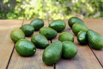 Tasty ripe avocados on wooden table outdoors