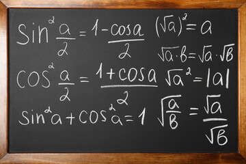 Many different math formulas written on chalkboard, closeup